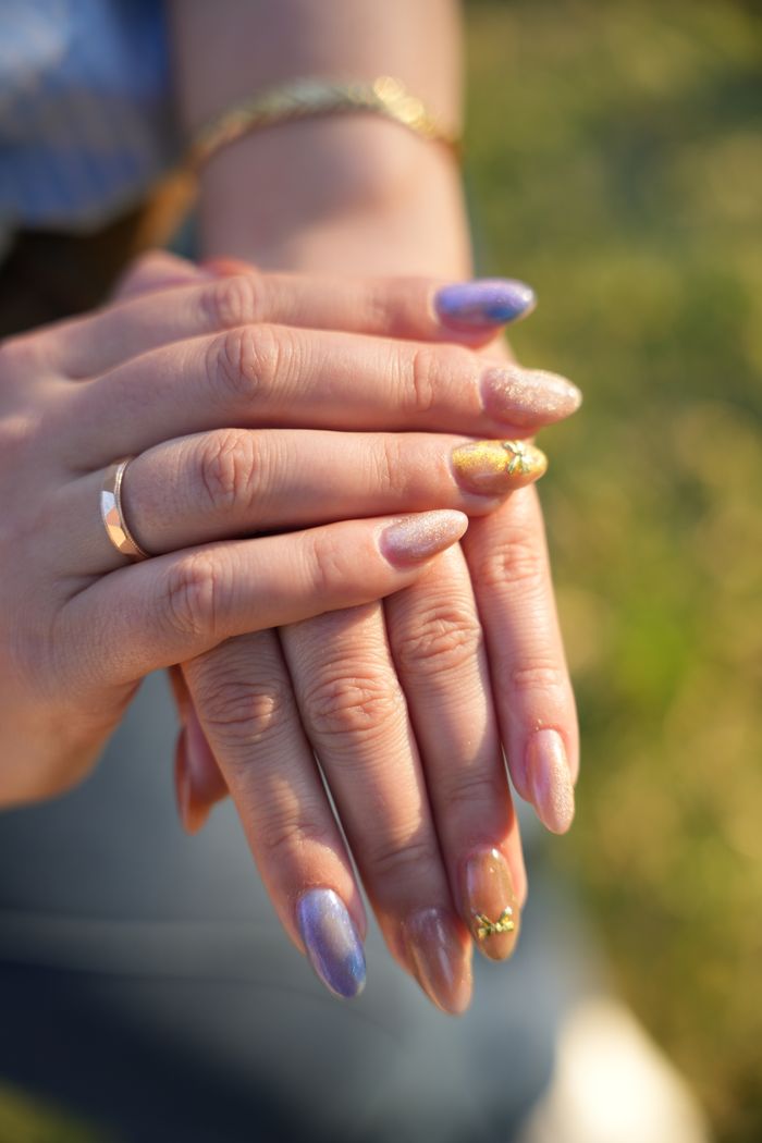 Elegant hands showcasing a vibrant multicolored manicure with unique designs.
