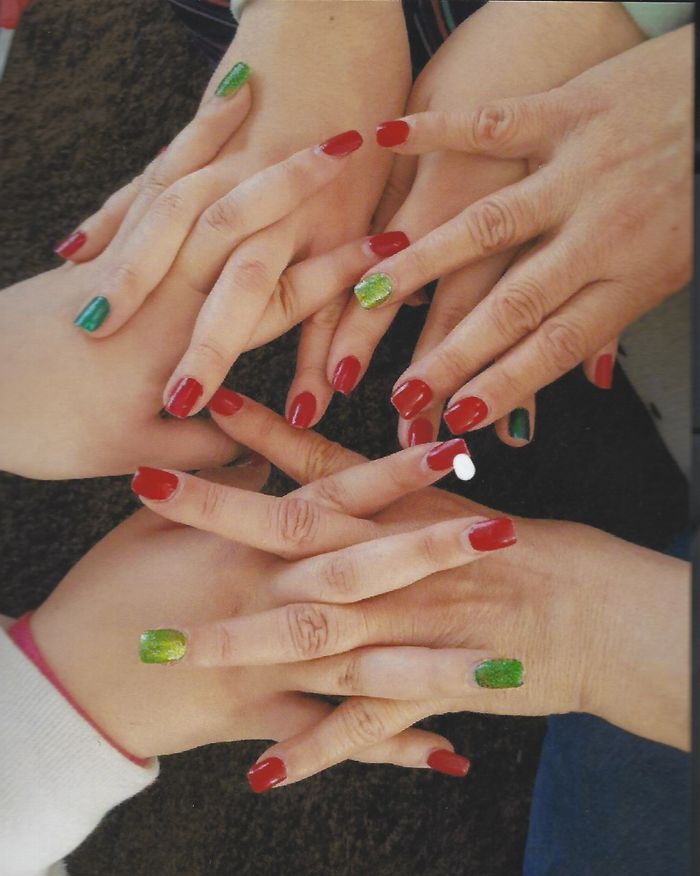 portfolio-06 Top view of multiple hands with red and green manicured nails in a festive display.